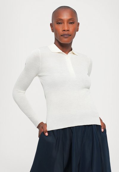 Polo a maniche lunghe bianco con un tessuto a maglia strutturata, caratterizzato da un colletto e una patta con bottoni, abbinato a una gonna blu scuro.