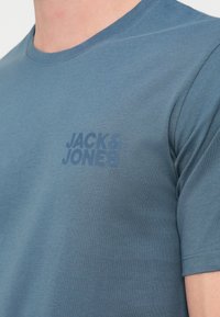 Μπλε βαμβακερό t-shirt με στρογγυλή λαιμόκοψη και κοντά μανίκια. Διαθέτει διακριτικό λογότυπο σε σκούρο απόχρωση στο στήθος. Ομαλή υφή.