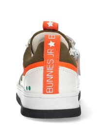 Valkoiset lenkkarit, joissa on ruskea mokkanahka kaulus, kirkkaan oranssi kantaosa, jossa lukee "BUNNIES JR", musta pohja ja vihreät korostukset alapään lähellä.