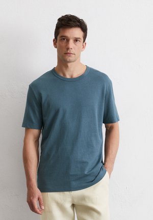 Koszulka z krótkim rękawem i okrągłym dekoltem w miękkim, ciemnozielonym kolorze; posiada luźny krój, gładką fakturę i minimalistyczny design.