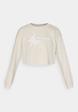 Beige lyhyt crop-top huppari pitkillä hihoilla, jossa on valkoinen grafiikka auringosta ja teksti "State of mind" painettuna etupuolelle.