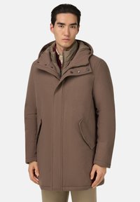 Manteau à capuche marron avec fermeture éclair, poches latérales et texture lisse. La couche intérieure est de couleur beige clair avec une fermeture éclair et un col montant.