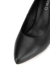 Czarna skórzana szpilka z wąskim noskiem, gładką fakturą i płaską podeszwą. Charakteryzuje się minimalnym szyciem i eleganckim designem.