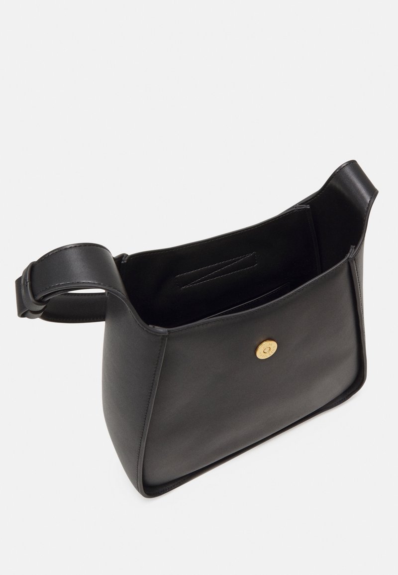 Sac à main en cuir noir avec une forme structurée, une seule bandoulière et un fermoir à pression doré. L'intérieur est non doublé et comprend une poche plaquée.