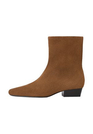 Brun mockaskinn ankelsko med en låg svart blockklack och spetsig tå, visad från utsidan på en vit bakgrund.
