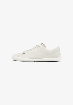 Minimalistische witte leren sneaker met een lage zool en witte veters, gezien vanaf de linkerkant op een witte achtergrond.