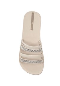 Sandalo scivoloso beige con due sezioni di cinturino trasparente decorate da applicazioni di strass, soletta testurizzata e dettaglio del logo.