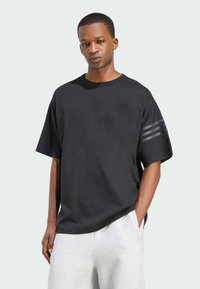 Black oversized T-shirt with short sleeves, crew neck, smooth texture, features three horizontal stripes in dark gray on the left sleeve.