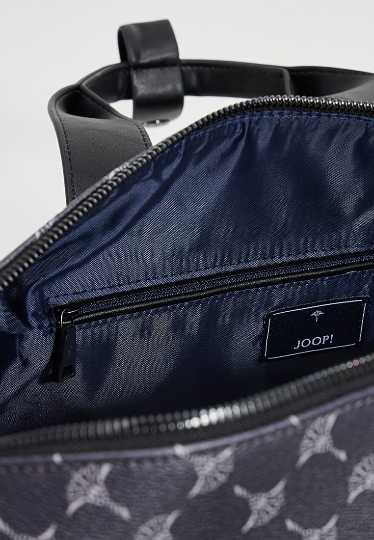 Schwarze Lederhandtasche mit einem Innenfutter aus navyfarbenem Stoff, ausgestattet mit einer Reißverschlusstasche und einem Etikett. Muster aus hellgrauen Designs auf der Außenseite.