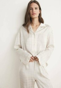 Lichtbeige zijde pyjama set met een knoopsluiting shirt met kraag en subtiel vierkant patroon, gecombineerd met losse broek en ruime mouwen.