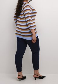 Striped knit top in blue and brown hues with three-quarter sleeves, paired with slim-fit navy trousers and black heeled mules.