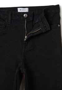 Jeans de denim negro con cremallera y cierre de botón. Incluyen una pretina reforzada y detalles de costura sutiles.