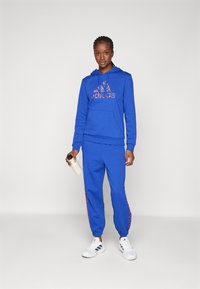 adidas Sportswear ESSENTIALS 3 STRIPES ANIMAL PRINT 7/8 PANT - Tracksuit bottoms - semi lucid blue/multicolor