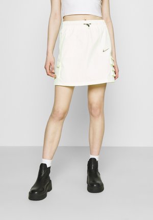 Lichtgroene Nike rok met een elastische tailleband, gerimpelde zijdetails en een gladde textuur, gecombineerd met zwarte plateau laarzen.