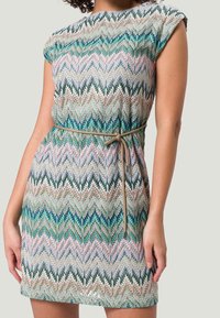 Vestido corto de manga corta, hecho de una tela liviana, con un patrón de zigzag multicolor en turquesa, verde y rosa; ceñido en la cintura.