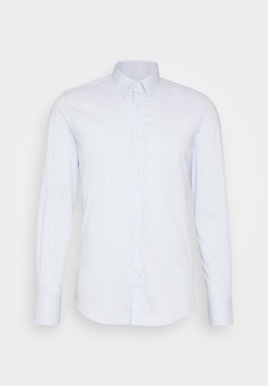 Svetlo modra srajca z dolgimi rokavi, izdelana iz gladkega blaga. Ima klasičen ovratnik, sprednje gumbe in ravno rob. Brez vzorcev ali dodatkov.