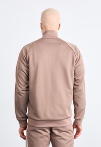 Brown, long-sleeve sweatshirt with a high collar and ribbed cuffs, made of smooth, soft fabric. Features raglan sleeves for comfort.
