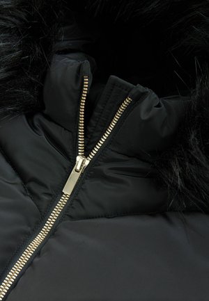 Giubbotto imbottito nero con cappuccio in pelliccia sintetica. Presenta una chiusura con cerniera dorata e una texture trapuntata sul corpo. Design di tessuto robusto.