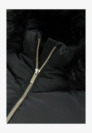 Črna puhovka z umetnim krznom na kapuci. Ima zlat zadrgo in prešito teksturo na telesu. Močna zasnova iz tekstila.