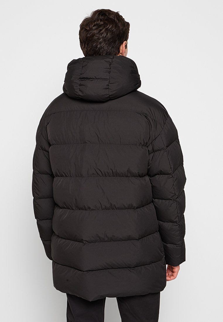 Zwarte geïsoleerde pufferjack met capuchon, voorzien van een quilted ontwerp, horizontale banen en een ontspannen pasvorm. Matte afwerking.