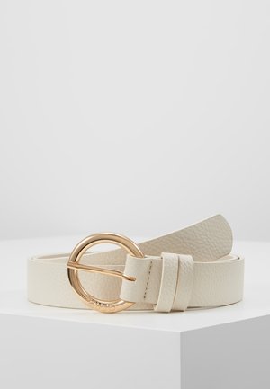 Cremefarvet tekstureret læderbælte med rund guldmetalspænde, der ligger sammenrullet på en hvid overflade mod en ensfarvet baggrund.