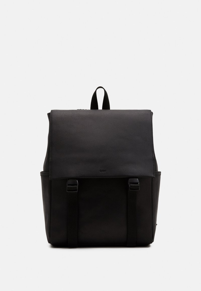 Sac à dos noir avec un extérieur en cuir lisse, fermeture à rabat, deux poches latérales et des bretelles réglables, présentant des détails de design minimalistes.