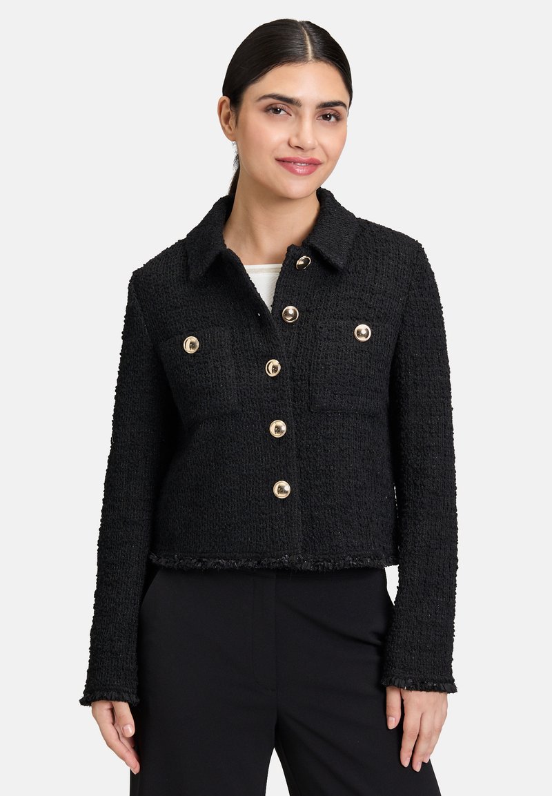 Sort tweedjakke med cropped design, tekstureret stof, knapper i guld-tone og to klaplommer. Har krave og frynset nederkant.