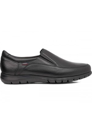 Zapato negro de cuero tipo mocasín con superficie lisa, puntera redondeada, acentos elásticos a los lados y suela de goma texturizada para mayor agarre.