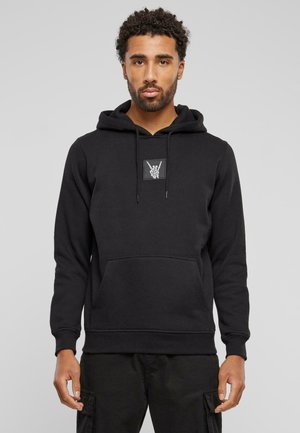 Sort hoodie lavet af blødt stof, med en kengurulomme, snører og et grafisk mærke af en håndgestus på brystet.