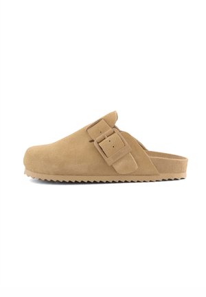 Hellbrauner Mokassin-Pantoffel aus Wildleder mit einem großen verstellbaren Schnallenriemen und einer profilierten Gummisohle, seitlich gezeigt.