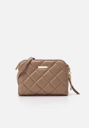 Lichtbruine doorgestikte leren crossbodytas met gouden rits, riem, kwastje en klein rechthoekig merkplaatje aan de voorkant.