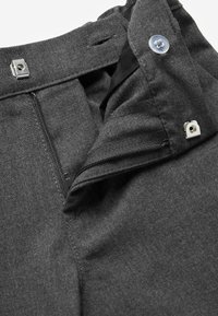 Donkergrijze broek met een rits- en knoopsluiting, een gladde stof textuur en een schone afwerking rond de tailleband en zakken.