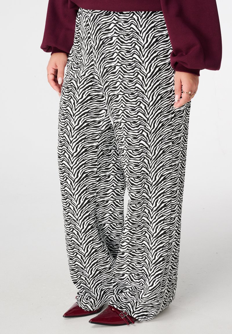 Zwart-witte zebraprint wijde broek met een zachte textuur. Draagt bijpassende puntige bordeauxrode hakken met een strak en taps toelopend ontwerp.