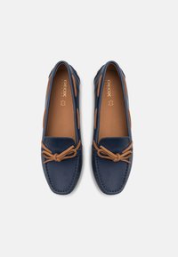 Mocassini in pelle navy con accenti marroni, caratterizzati da una punta arrotondata, bordi cuciti e un fiocco decorativo sul davanti per un tocco in più.