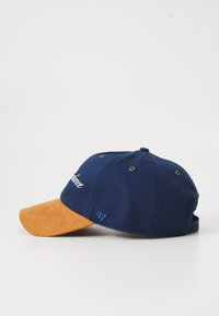 Navy blue cap with a suede orange bill, featuring embroidered "Balance" text and small details, like ventilation holes and a back strap.