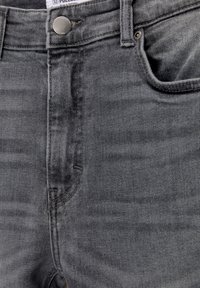 Jeans de mezclilla gris con ajuste Slim, diseño de cinco bolsillos, con cierre de botón y detalles de textura sutiles.