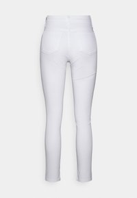 Jeans blancos ajustados, con una cintura alta, diseño de cinco bolsillos, material vaquero y textura suave. Sin patrones ni acentos visibles.