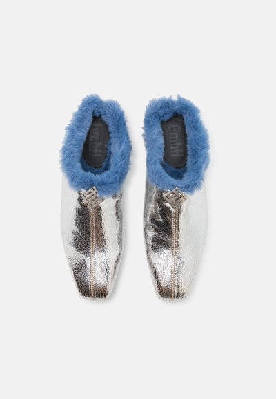Metalliske sølvfargede slip-on sko med blå faux fur fôr og teksturert overflate. Har glidelås og spiss tådesign.