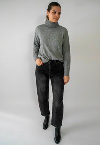 Grijze coltrui met een structuurpatroon, gecombineerd met zwarte high-waisted jeans en zwarte enkellaarsjes. Eenvoudig en nauwsluitend ontwerp.