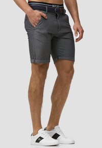 Grå denimshorts med en opkrøllet kant, med sidelommer og et vævet bælte. Kombineret med hvide sneakers med sorte detaljer.
