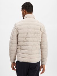 Lichtbeige pufferjack met horizontaal gebreid ontwerp, hoge kraag en elastische manchetten. Glad fabric textuur, minimalistische stijl.