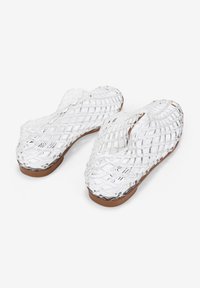 Chanclas de plástico transparentes con una textura trenzada, que presentan una suela marrón. El diseño incluye un patrón geométrico en toda la parte superior.