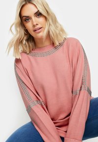 Vaaleanpunainen collegepaita, jossa on pitkät hihat ja hopeaa niittiä olkapäillä ja hihoissa. Pehmeä materiaali ja rento malli.