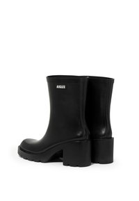 Black rubber ankle boots with a block heel, featuring a rounded toe and a logo on the back. Smooth texture and minimalist design.