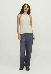 Ανοιχτό γκρι αμάνικο τοπ με ραβδωτή υφή, συνδυασμένο με σκούρες μπλε τζιν παντελόνες με φαρδιά σχεδίαση και μαύρα παπούτσια. Απλή, καθημερινή εμφάνιση.