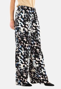 Pantaloni a gamba larga con una stampa astratta in bianco, nero e blu. Presentano un elastico in vita e una consistenza del tessuto morbida e fluida.