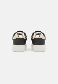 Sneaker nere con una toma in pelle testurizzata, dettagli metallici dorati sul tallone, suole in gomma bianche e colli imbottiti per il comfort.