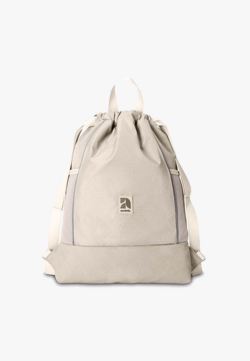 Zaino a cordoncino di un beige chiaro realizzato in tessuto testurizzato, dotato di un fondo solido, tasche laterali in rete e una patch con logo sulla parte anteriore.
