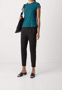 Teal kortärmad t-shirt med spetsdetaljer, svarta skräddarsydda byxor med veck, och svarta öppen-tåhelar. Svart axelväska ingår.