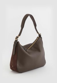 Brązowa skórzana torba na ramię o teksturowanej powierzchni, złotym zamku i ciemnym zamszowym akcentem. Wygięty kształt z pojedynczym regulowanym paskiem.